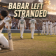 Dejected Babar Azam kneels beside his bat as Pakistan’s players walk away and West Indies celebrate their first Test victory with jubilant home fans.
