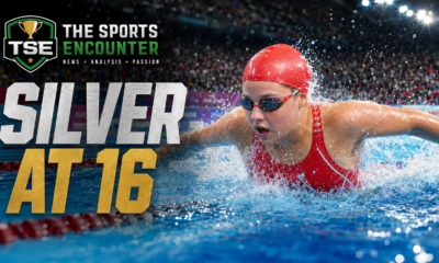 VFX cinematic image of an Amalie Smith-inspired swimmer racing through the pool in a red cap and red England-style swimsuit, with water splashing around her, The Sports Encounter logo, and the headline “Silver at 16.”