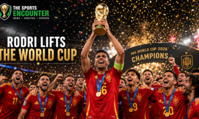 Rodri lifts the FIFA World Cup 2026 trophy as Spain’s players celebrate on the winners’ podium beneath gold confetti and stadium lights.