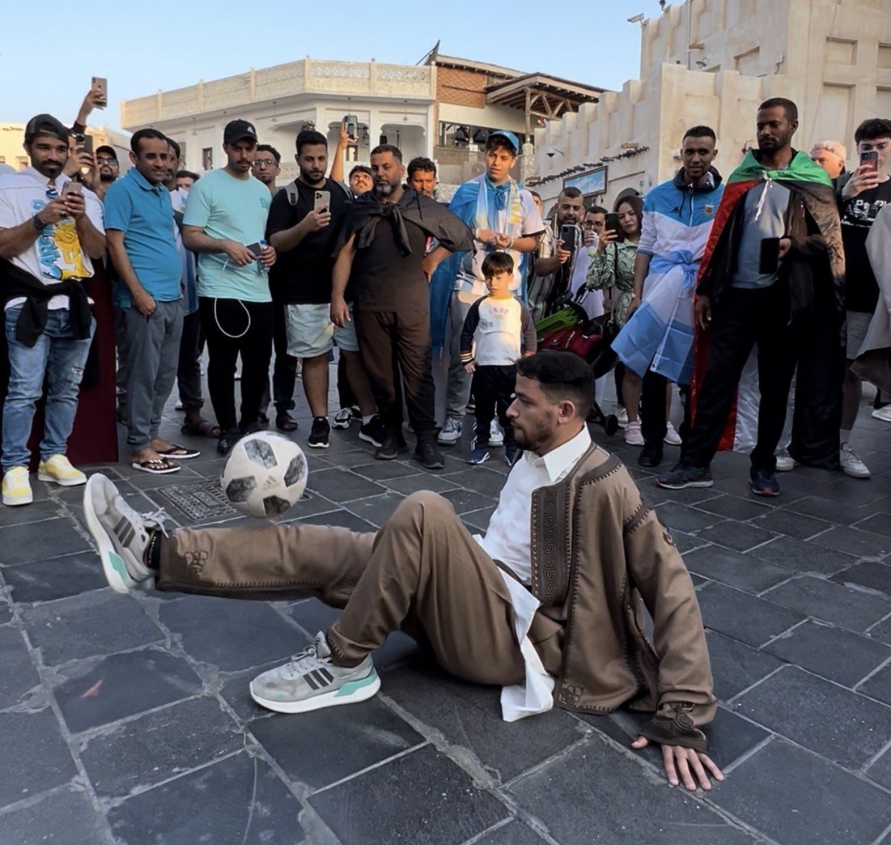Faraj Rahil performing seated freestyle football in Libyan attire in front of spectators