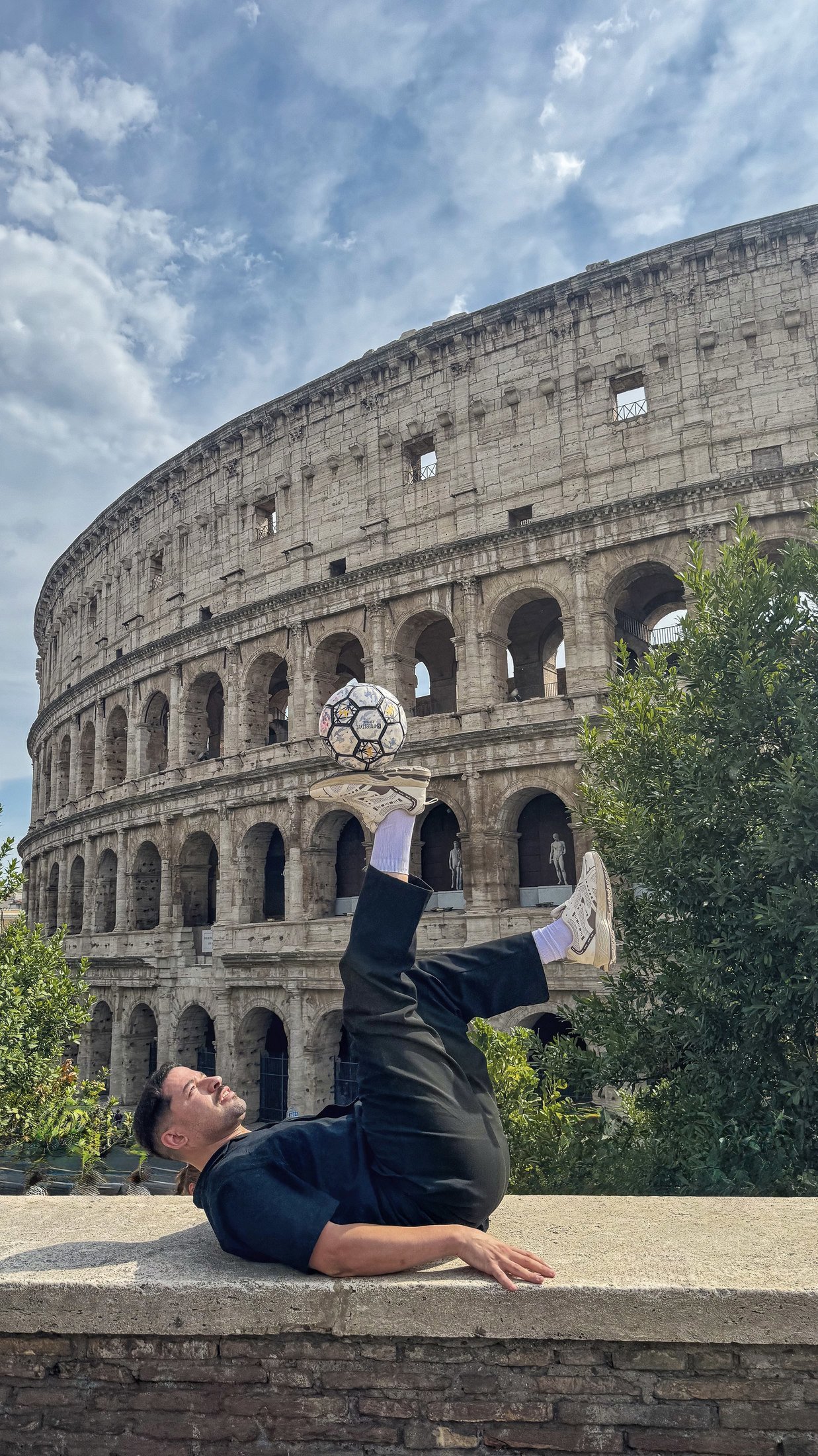 Faraj Rahil controlling a football while balanced on the ground near the Colosseum