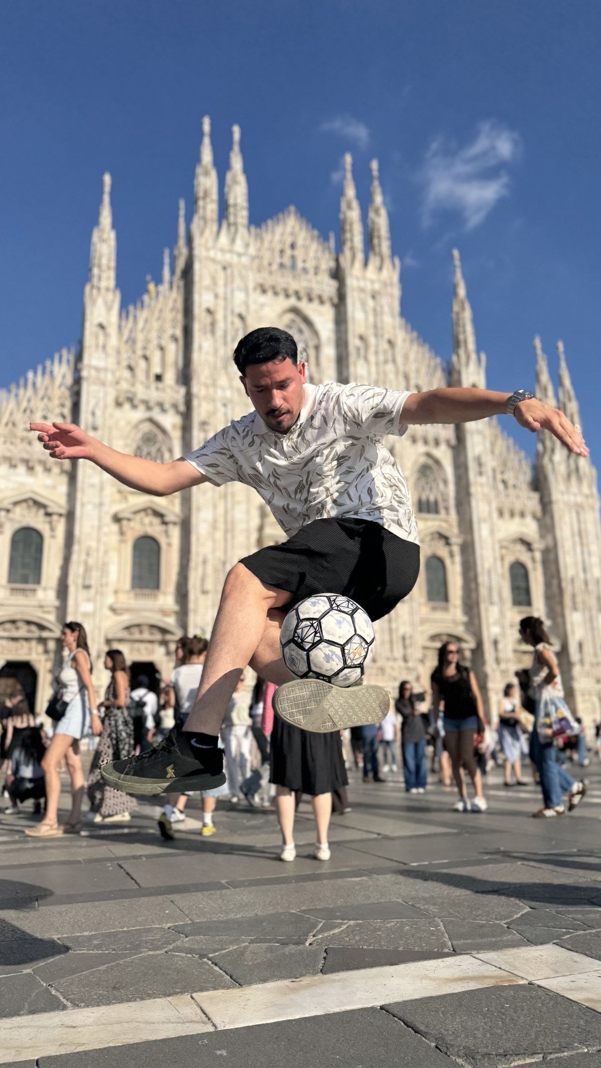 Faraj Rahil performing freestyle football near an ornate cathedral